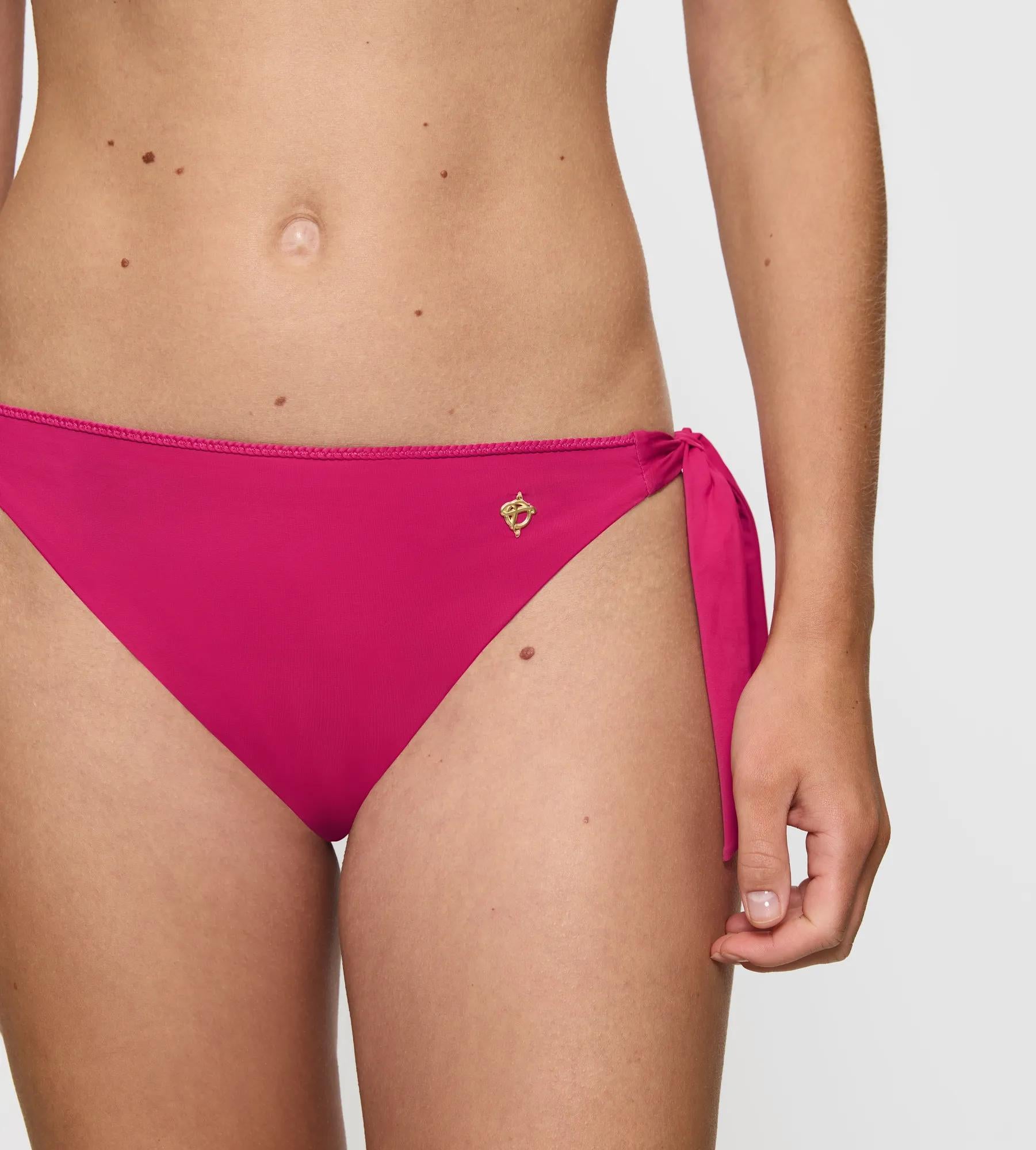 Summer Twist bikini bottom in vibrant pink with adjustable side ties and decorative waist detail.