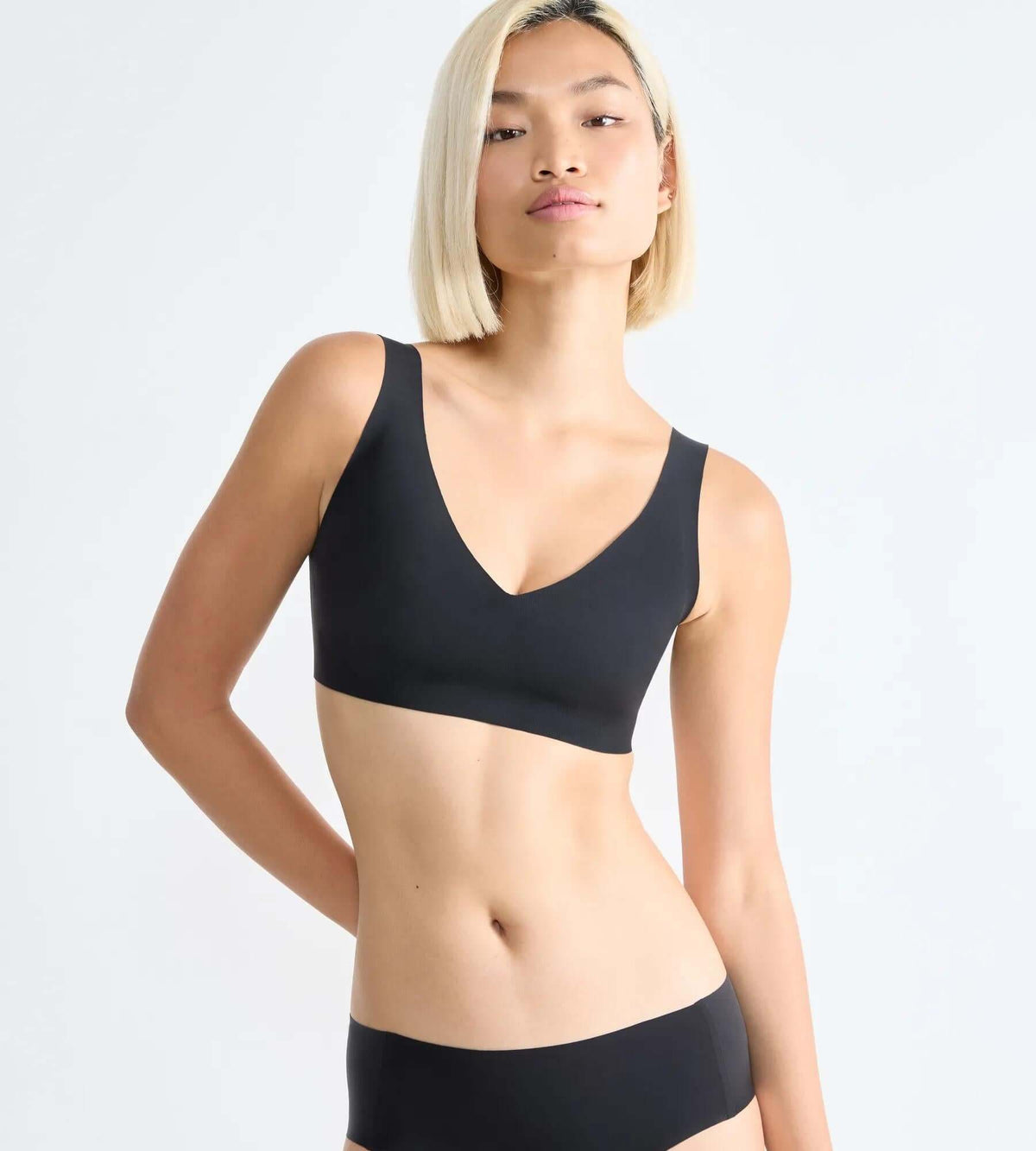 Model wearing sloggi ZERO Feel bralette in black, showcasing seamless design and V-neck style.