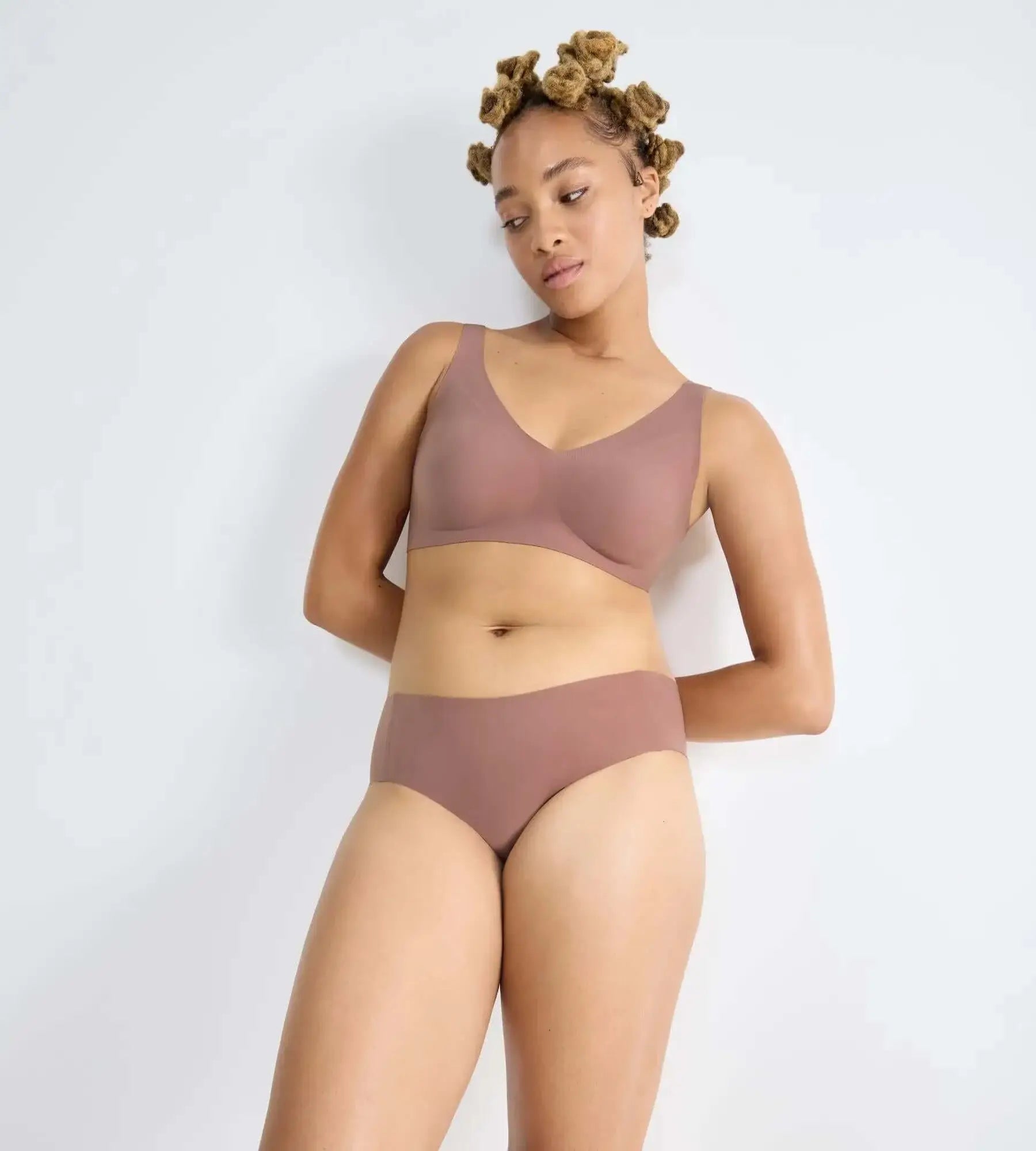 Model wearing sloggi ZERO Feel seamless hipster briefs and matching bralette in a soft brown color.