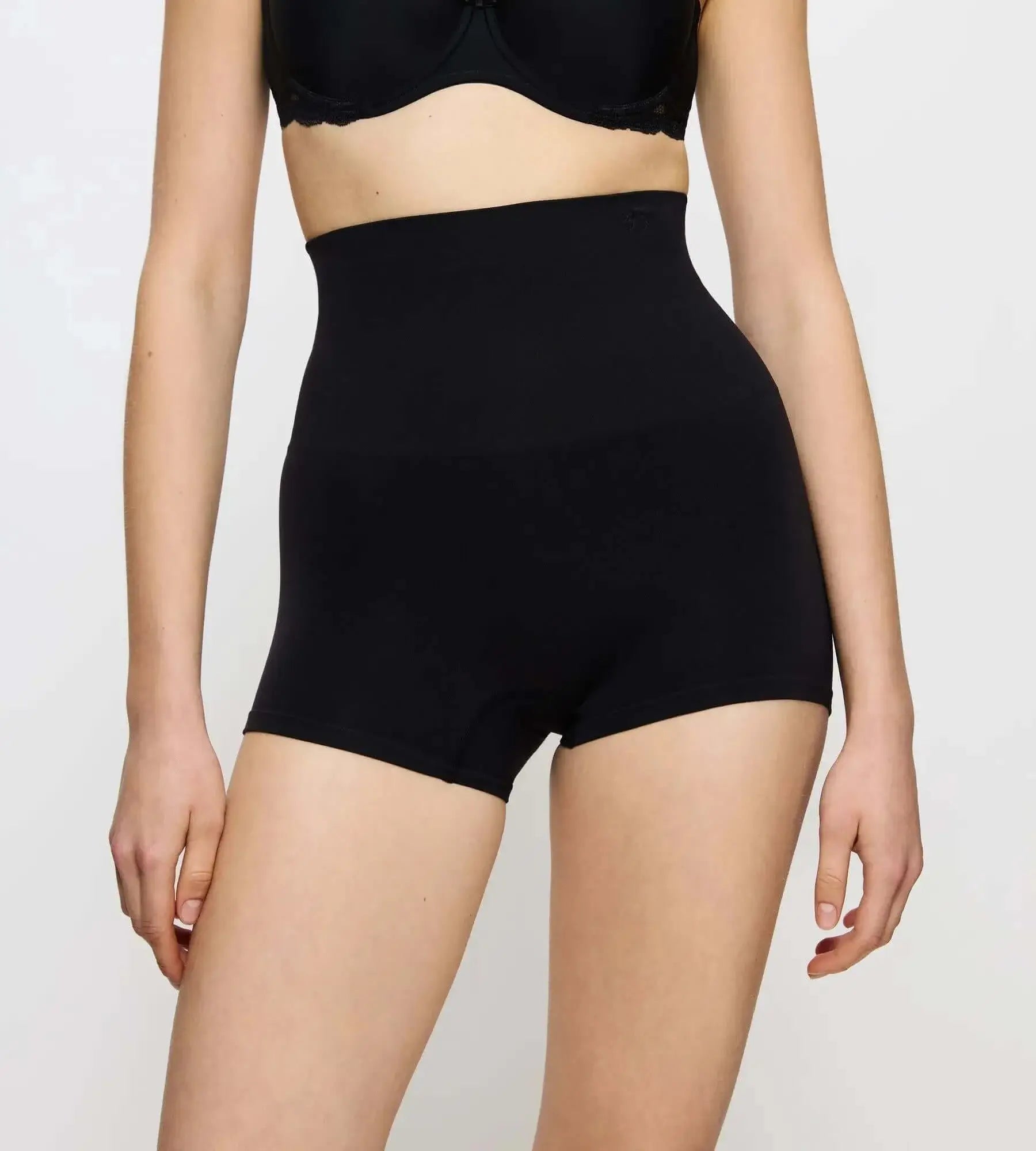 Woman wearing Triumph Soft Sculpt black briefs with smooth, soft knit fabric and high-rise design for maximum comfort.